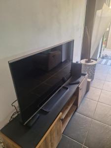 a large flat screen tv sitting on a wooden entertainment center at L' ecrin de douceur in Saint-Benoît