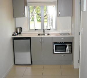 a kitchen with a sink and a microwave at St Johns court motel in Milton