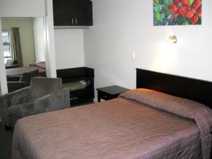 Habitación de hotel con cama y silla en St Johns court motel, en Milton