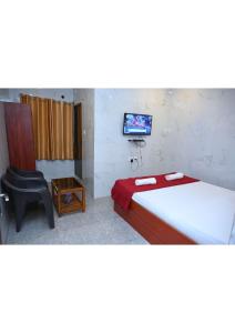 a room with two beds and a tv and a chair at Netrani Residency in Māvalli