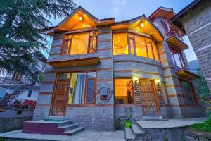 a large house with a lot of windows at Pine Wood Chalet in Manāli