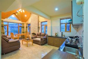 a kitchen with two couches and a living room at Pine Wood Chalet in Manāli