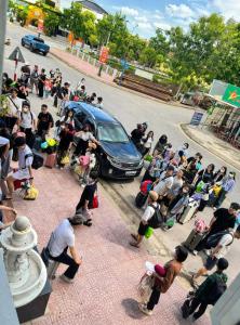 a crowd of people standing around a car on a street at White Rose Hotel in Dong Hoi