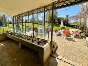 a screened in porch with a bench with plants at Le Pavillon, Grand Manoir du XVIIe avec Piscine, Bain Nordique et accès privé à la Charente in Alloué