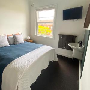 a bedroom with a bed and a sink and a window at Blues Point Hotel in Sydney