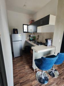 a small kitchen with a refrigerator and two blue chairs at La gloria hospedajes in Cuernavaca
