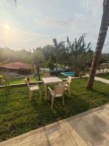 a table and chairs in the grass near a pool at La gloria hospedajes in Cuernavaca