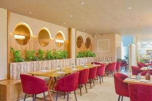 a restaurant with wooden tables and red chairs at HOTEL HIVE in Mājra
