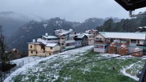 a group of buildings on a snow covered hill at Indu Homestay in Shimla