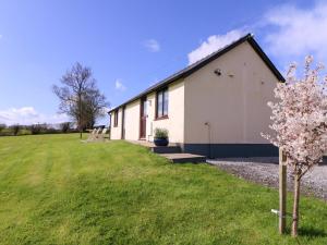 a building with a green field next to it at Sunny Cottage in Brecon