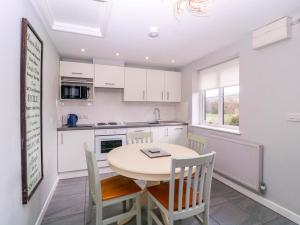 a kitchen with a table and chairs and a kitchen with white cabinets at Sunny Cottage in Brecon