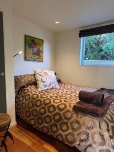 a bedroom with a bed with a pillow and a window at Raumati Sunsets in Raumati Beach
