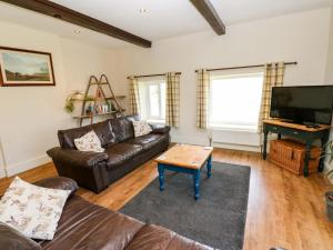 a living room with a leather couch and a flat screen tv at The Hayloft in Ripon