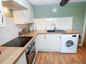 a kitchen with white cabinets and a washer and dryer at The Hayloft in Ripon