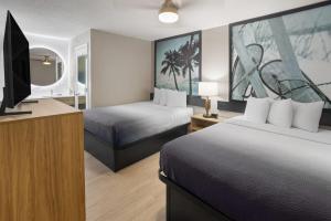 a hotel room with two beds and a flat screen tv at Super 8 by Wyndham Ellenton Bradenton Area in Ellenton +41 photos