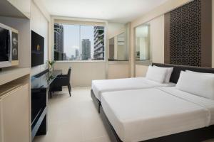 a bedroom with a bed and a desk and a window at Mandarin Hotel Managed by Centre Point in Bangkok