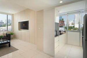 a kitchen with white cabinets and a living room at Mandarin Hotel Managed by Centre Point in Bangkok