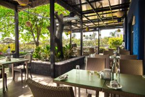 a restaurant with green tables and chairs and trees at Acron Waterfront Resort in Baga