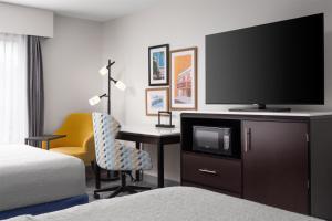 a hotel room with a television and a desk with a chair at Hampton Inn Augusta Fort Eisenhower in Augusta
