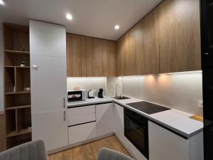 a kitchen with white appliances and wooden cabinets at Apartament white Arena in Chişinău +37 photos