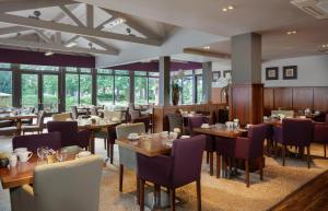 a restaurant with wooden tables and chairs and windows at DoubleTree by Hilton Stratford-upon-Avon, United Kingdom in Stratford-upon-Avon +26 photos