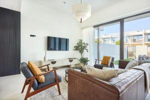 a living room with a couch and chairs and a tv at Frank Porter - Nara, The Valley in Dubai