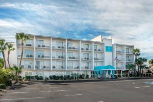 a large white hotel with palm trees and a parking lot at Inn on Destin Harbor, an Ascend Collection Hotel in Destin
