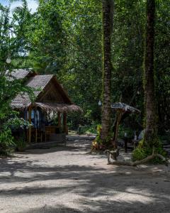 a dog sitting in front of a building with trees at Bananas Resort & Restaurant in Tha Lane Bay