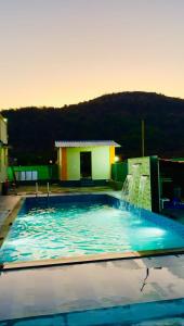 a swimming pool with a water fountain in front of a house at Kohinoor villa in Lonavala