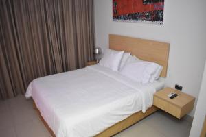 a bedroom with a white bed with a wooden headboard at Radisson Diamond Barranquilla in Barranquilla