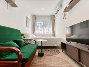 a living room with a green couch and a flat screen tv at 8 Min Walk to IconSiam I BTS near Pier in Bangkok