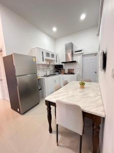 a kitchen with a wooden table and a refrigerator at Cozy Poolvilla Pattaya in Bang Lamung