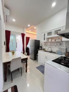 a white kitchen with a table and a dining room at Cozy Poolvilla Pattaya in Bang Lamung +5 photos
