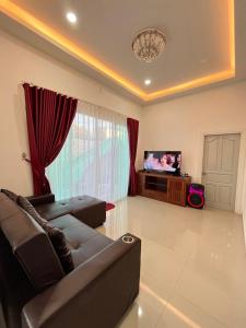 a living room with a couch and a television at Cozy Poolvilla Pattaya in Bang Lamung