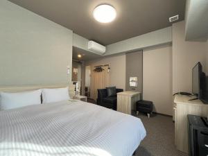 a hotel room with a bed and a chair at Hotel Route Inn Imabari in Imabari