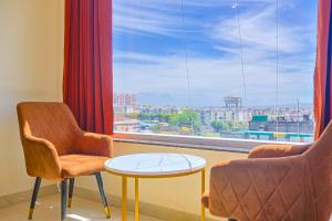 a room with two chairs and a table and a large window at HOTEL HIVE in Mājra