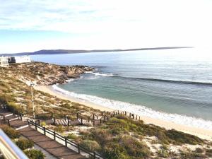 a beach with benches next to the water at Langebaan Beach Towers in Langebaan