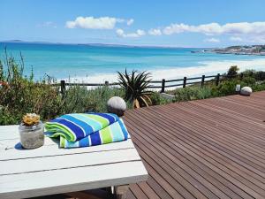 a bench with a pillow sitting on a deck with the beach at Langebaan Beach Towers in Langebaan