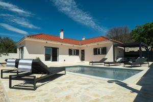 a house with a swimming pool and two lounge chairs at Casa Mia in Danilo Biranj