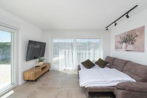 a white living room with a couch and a tv at Casa Mia in Danilo Biranj