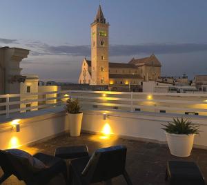 a rooftop patio with chairs and a clock tower at night at White House in Trani