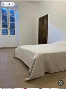 a white bedroom with a bed and a window at F2 rue fesch in Ajaccio