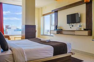 a bedroom with a bed and a tv on the wall at HOTEL HIVE in Mājra