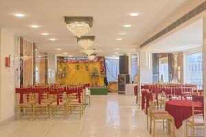 a banquet hall with tables and chairs and a stage at HOTEL HIVE in Mājra