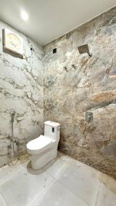a bathroom with a toilet and a stone wall at HOTEL RR Grand in Varanasi