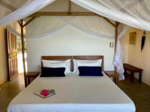 a bedroom with a large white bed with a canopy at Komba on the Rocks in Nosy Komba