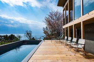 a deck with chairs and a swimming pool on a house at KAMOME SLOW HOTEL in Awaji