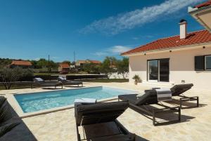 a swimming pool with chairs and a house at Casa Mia in Danilo Biranj