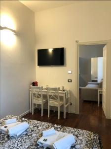 a room with a table with chairs and a television on the wall at Camera Albergo - Suites Mansion in Rozzano