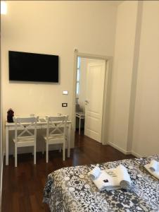a room with a table and a television on the wall at Camera Albergo - Suites Mansion in Rozzano